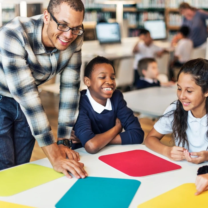 Male teacher helping a group of primary school children during a lesson
