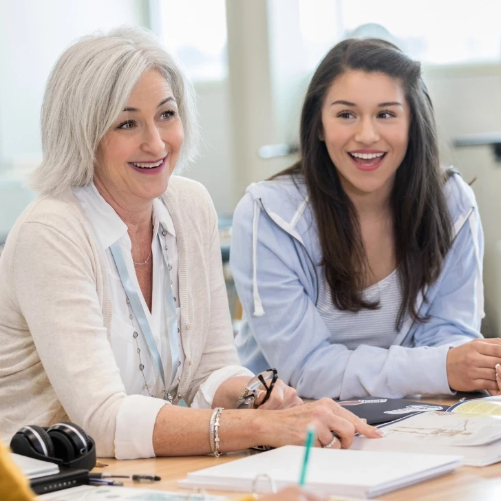Two female teachers laughing during a school meeting